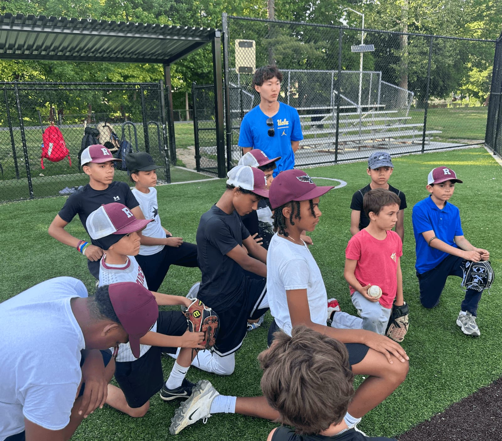 Cooper Won coaching a kneeling youth team in a huddle on a turf field