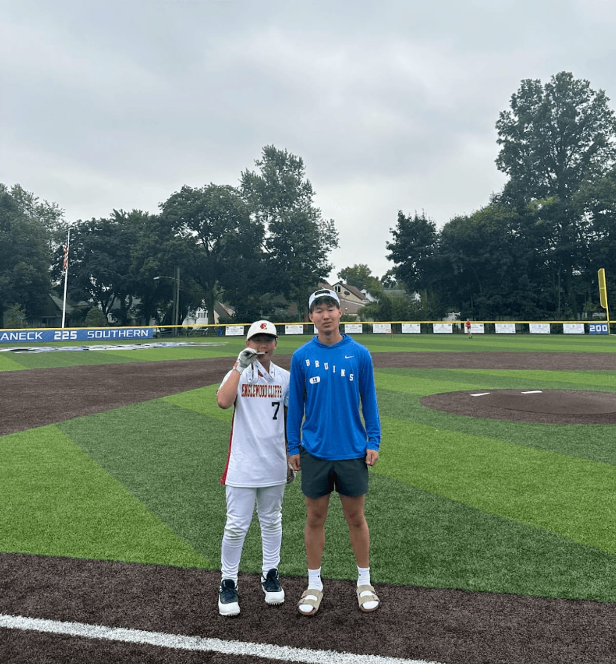 Cooper Won standing beside a young player in an Englewood Cliffs number 7 uniform on a baseball field